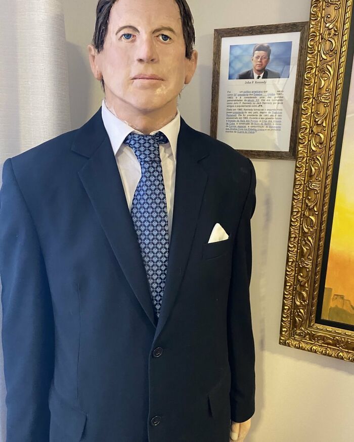 Wax sculpture of a famous figure in a suit and tie, showcasing creepy and hilarious details by the artist.