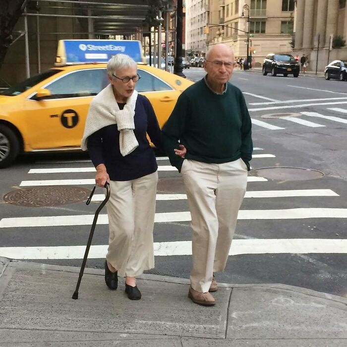Stylish grandparents walking arm in arm on a city street, showcasing cool and timeless outfit choices.