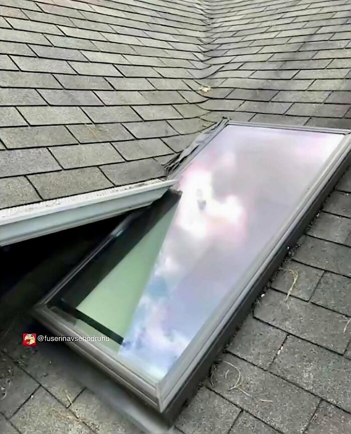 Damaged roof design with a broken skylight poorly installed on shingled roofing showing construction flaws.