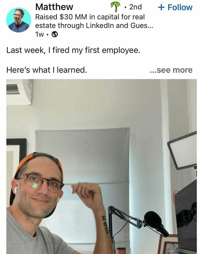 Man wearing glasses and a backward cap, smiling and sitting at desk with microphone, illustrating hustle culture burnout.