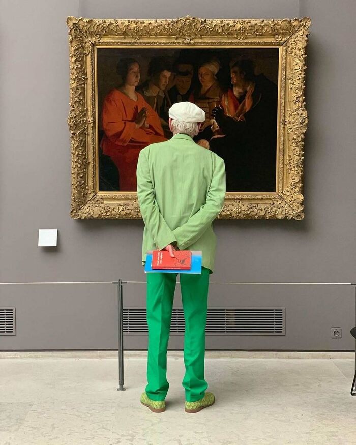 Elderly man in stylish green outfit admiring art, showcasing cool and stylish grandparents fashion inspiration.