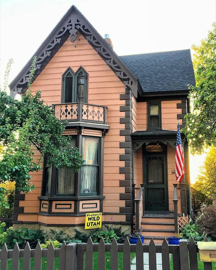 Victorian-style old home with decorative trim, wooden fence, and lush greenery, showcasing charming and lovely old homes to move into.
