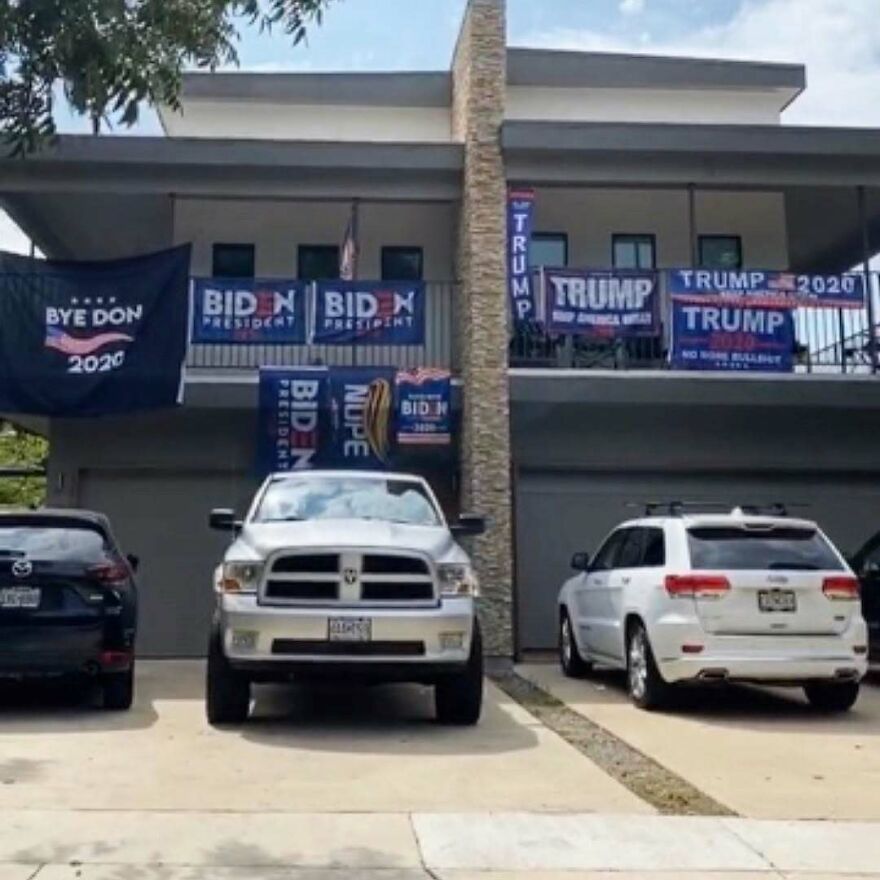 Apartment building with multiple political flags displayed on the balcony in a quiet residential area with no neighbors.