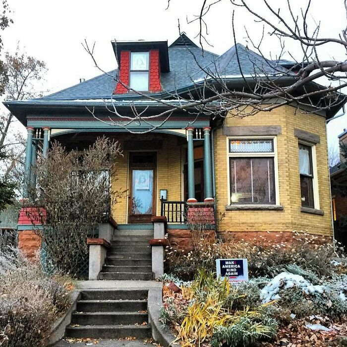 Yellow old home with a covered porch, decorative columns, and winter garden, showcasing charming old homes appeal.