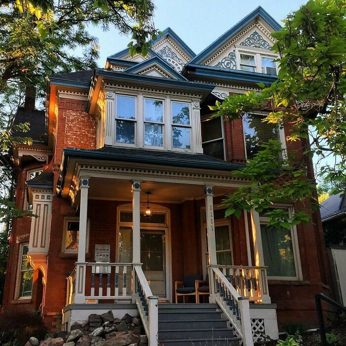 Victorian style old home with detailed trim and a welcoming porch surrounded by trees in a peaceful neighborhood.