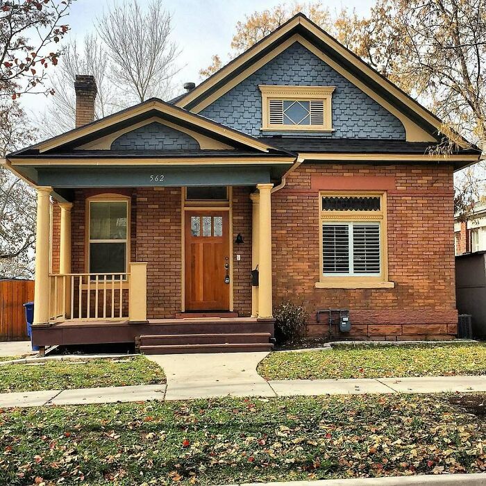 Charming old home with brick exterior, wooden porch, and blue shingled gable roof, perfect for moving into an adorable old home.