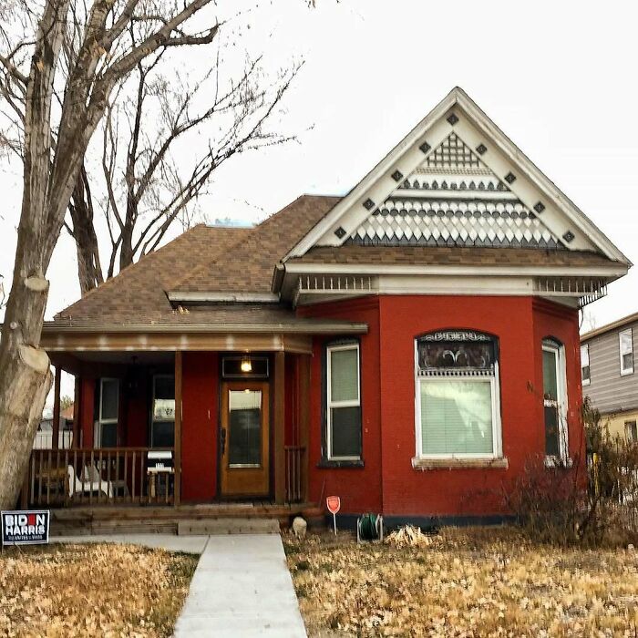 Charming old home with detailed gable, front porch, and brick exterior surrounded by dry grass and bare trees.