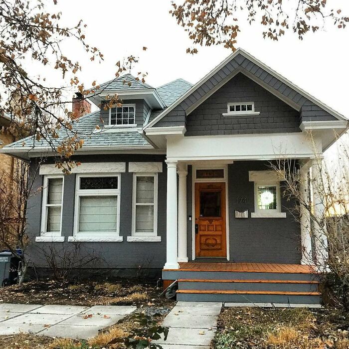Charming old home with gray exterior and wooden door, showcasing classic architecture and inviting front porch.