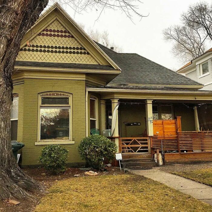 Charming old home with classic architectural details, green exterior, and a cozy front porch surrounded by a yard.