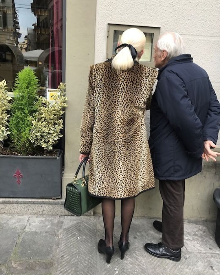 Stylish grandparents wearing a leopard print coat and dark jacket, showcasing cool and fashionable outfits on the street.
