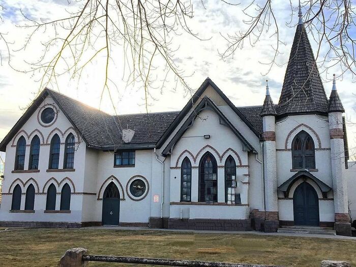 Charming old home with unique medieval-style architecture and pointed arch windows under a cloudy sky.