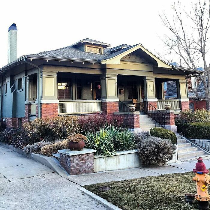 Charming old home with brick and wood exterior, front porch, and landscaped garden in a quiet neighborhood.