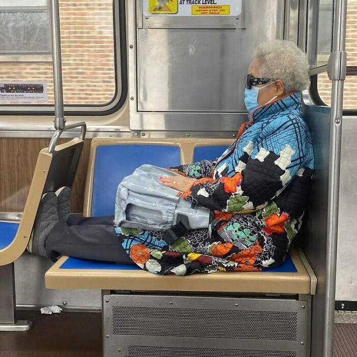 Elderly woman wearing a colorful floral jacket and sunglasses, sitting stylishly on public transit, showcasing cool grandparents fashion.