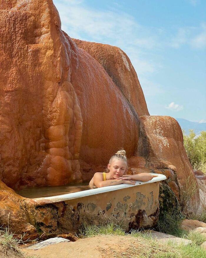 A woman relaxing in an old bathtub outdoors near large rock formations, evoking chilling messages before going missing.