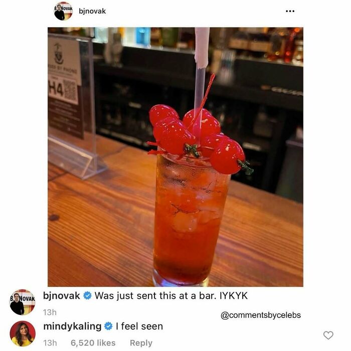 Cocktail with bright red cherries on a wooden bar counter, featuring a playful celebrity comment interaction.