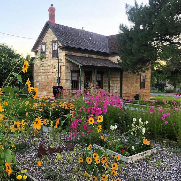 Old charming stone home surrounded by colorful flowers and lush greenery, perfect adorable and lovely old homes.