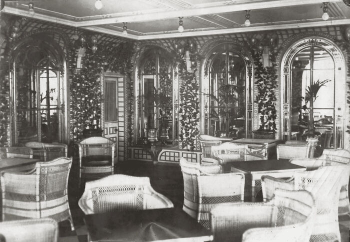 Interior view of a rare historical photo showing the Titanic’s luxurious wicker seating area and ornate wall decor.