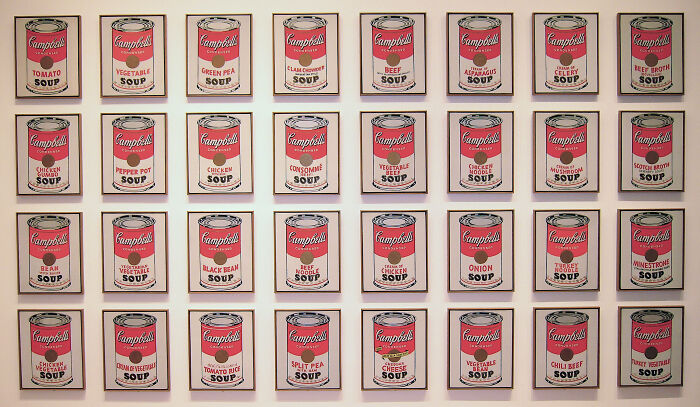 Wall display of iconic Campbell’s soup can paintings showcasing timeless paintings and their legendary stories.