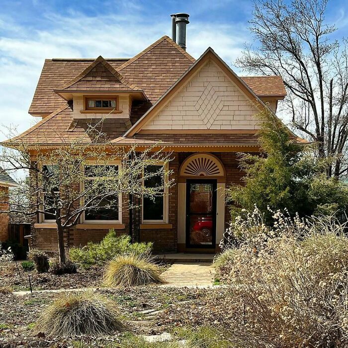 Charming old home with detailed woodwork and a lush, natural garden setting in early spring light.