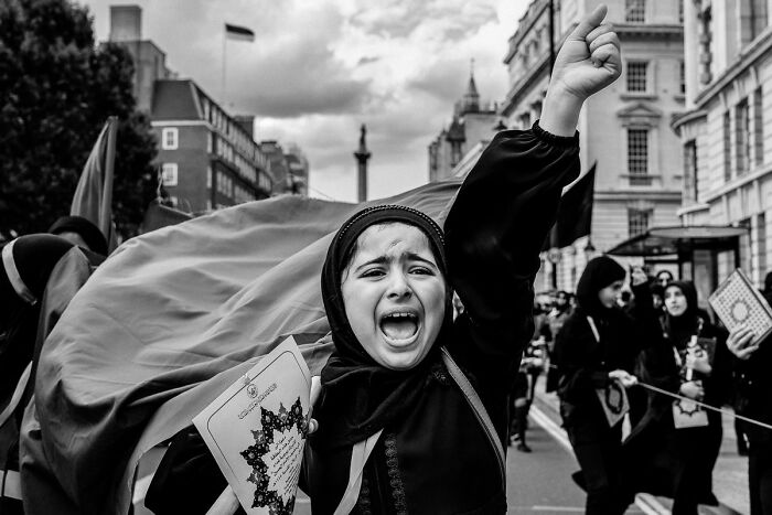 Black-and-white photo of a woman passionately protesting in a street, featured in award-winning exposure one photos.