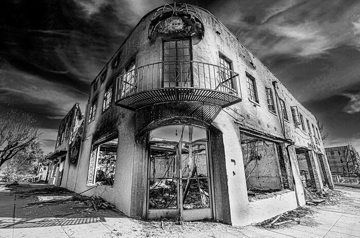 Black-and-white photo of a dilapidated building with dramatic skies, showcasing award-winning photography style.