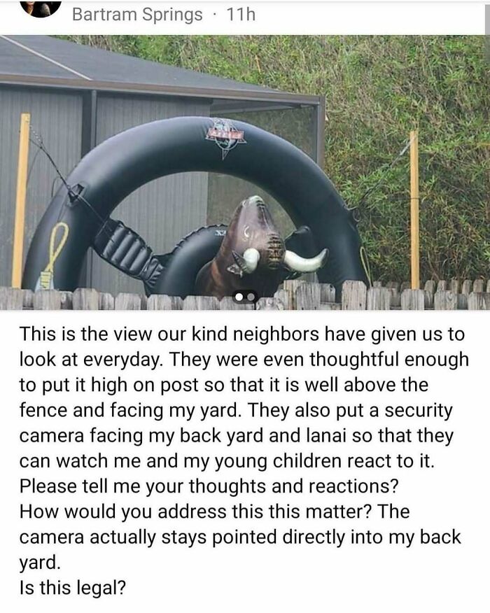 Inflatable bull decoration placed above fence by unbearable neighbors with surveillance camera facing backyard.