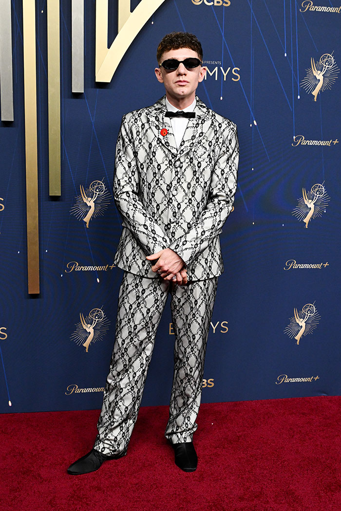 Hombre con traje estampado blanco y negro en la alfombra roja, mostrando estilo en los Emmys 2025.