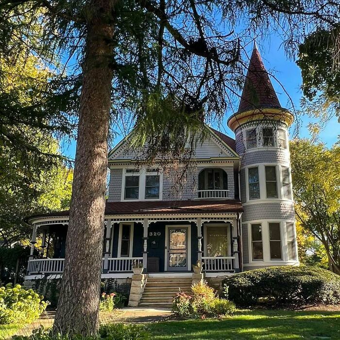 Victorian-style old home with turret, wraparound porch, and lush greenery, showcasing adorable and lovely old homes charm.
