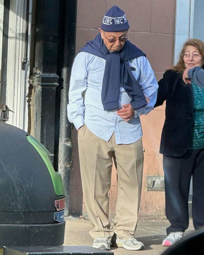 Elderly man showcasing cool and stylish grandparents fashion with a beanie, light shirt, and khaki pants on a sunny day.