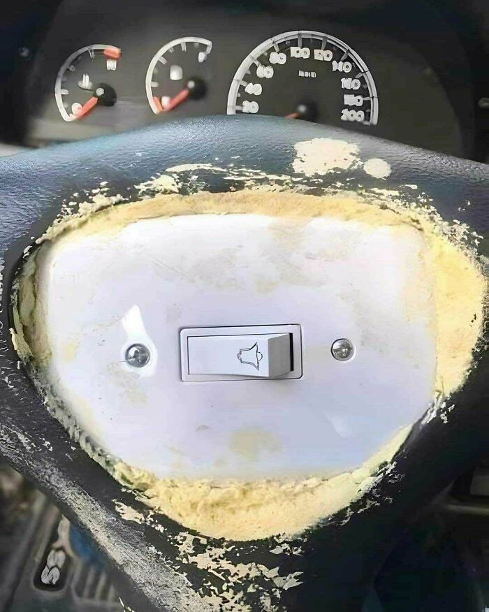 Poorly executed construction and design featuring a doorbell switch installed on a vehicle steering wheel.