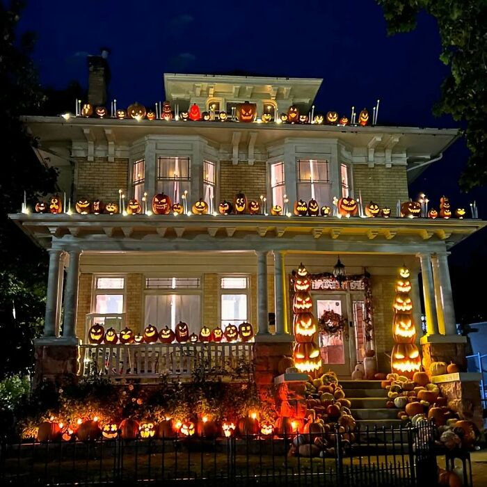 Old homes decorated with glowing carved pumpkins for Halloween at night, creating a warm and festive atmosphere.
