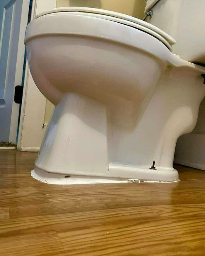 Toilet installed on wood flooring with poorly applied sealant, an example of construction and design gone wrong.