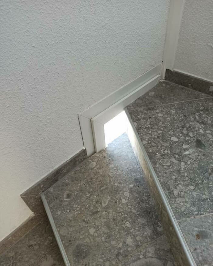 Construction design with a small, impractical door at the base of stone stairs letting in light but no access.