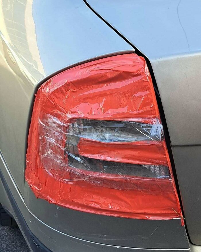Car tail light covered with red tape as a makeshift repair in a construction design fail example.