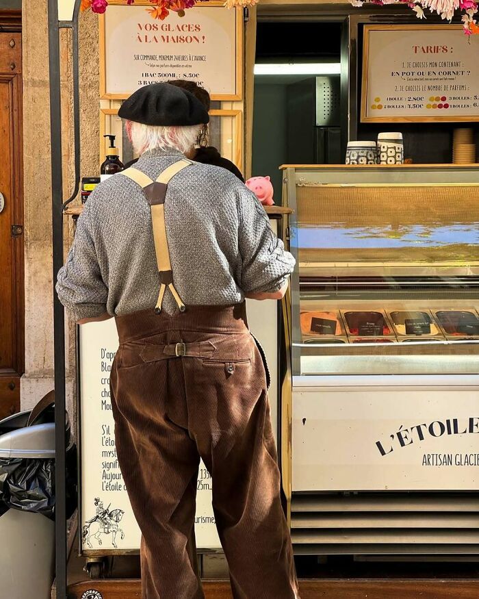 Older man in stylish suspenders and beret standing at an artisan ice cream shop, showcasing cool and stylish grandparents fashion.