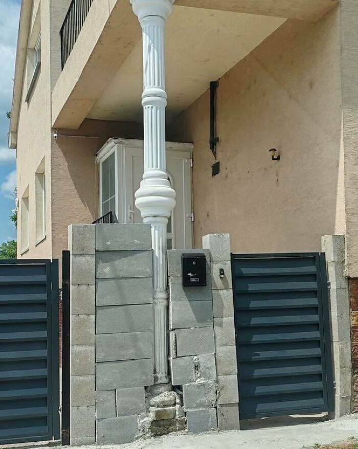 Construction design with a flawed concrete wall and a decorative column awkwardly placed in the middle of a gate entrance.