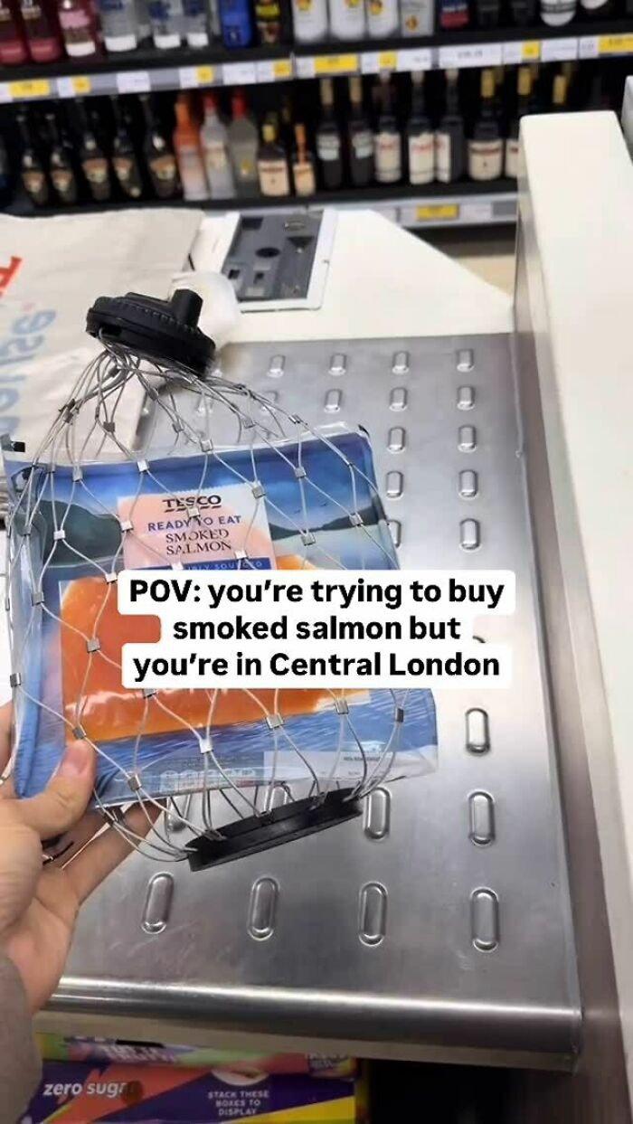 A person holds smoked salmon in a theft prevention cage at a London store, representing great London memes humor.