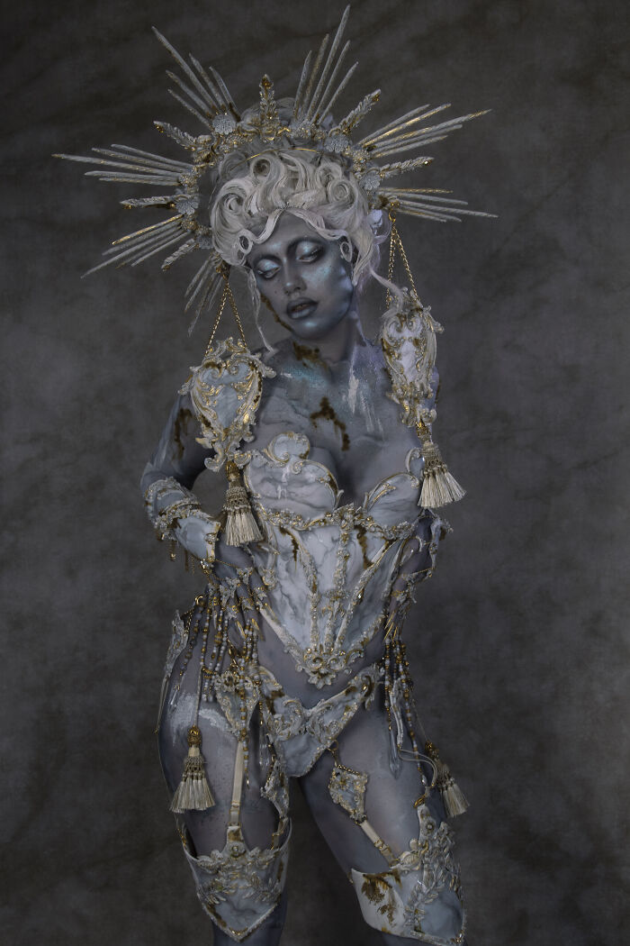 Person transformed into a haunting Halloween character wearing elaborate gold and white costume with detailed makeup and headpiece.