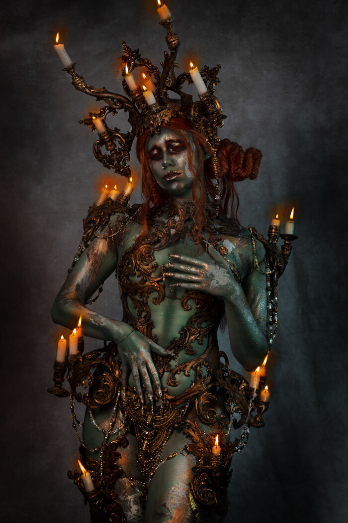 Haunting Halloween character with green skin and elaborate candlelit costume, showcasing a detailed artistic transformation.