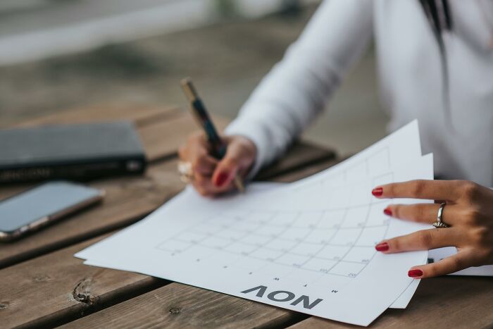 Person with red nails marking dates on a November calendar, highlighting tricky deal breakers in life decisions.