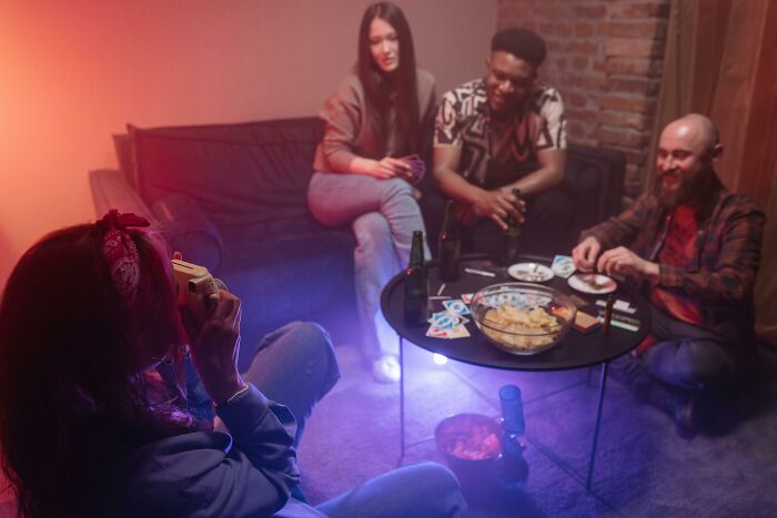 Group of friends sitting on couch and floor, playing cards and socializing, illustrating tricky deal breakers in life.