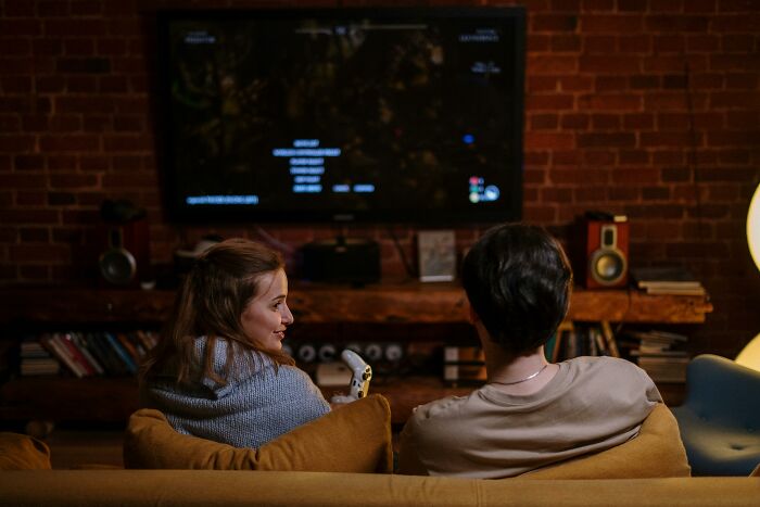 Two people sitting on a couch playing video games, illustrating tricky deal breakers in relationships and life decisions.
