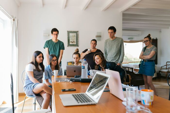 Group of young adults focused on a laptop screen during a discussion about tricky deal breakers in life decisions.