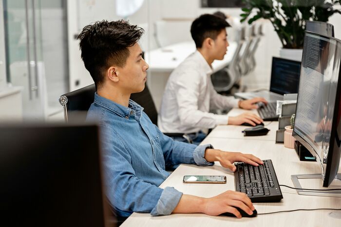 Two men focused on computer screens in an office setting, contemplating tricky deal breakers across life situations.