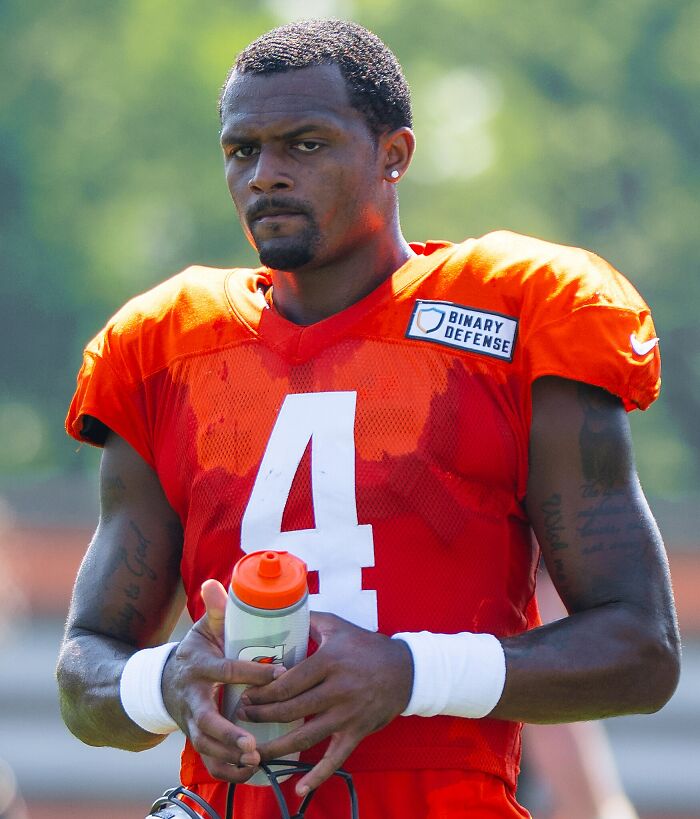 Athlete in orange football jersey holding water bottle during practice, representing highest paid athletes 2025.