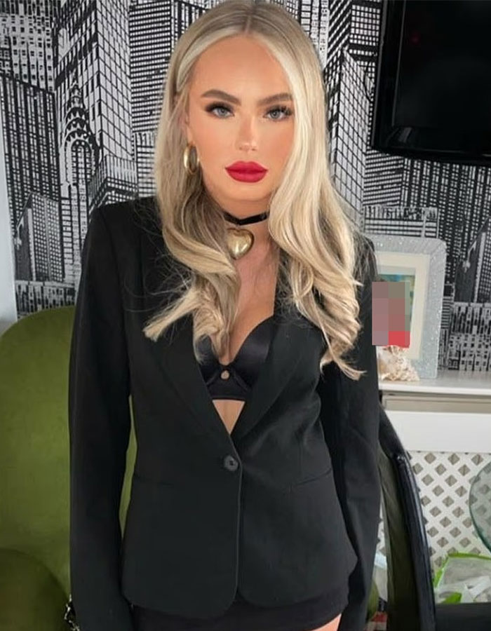 Blonde woman wearing black blazer and heart necklace, representing life inside infamous Dubai prison for British student.