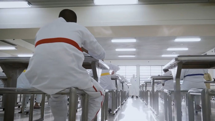 Men in white uniforms sitting inside an infamous Dubai prison, showing daily life for inmates jailed for substance possession.