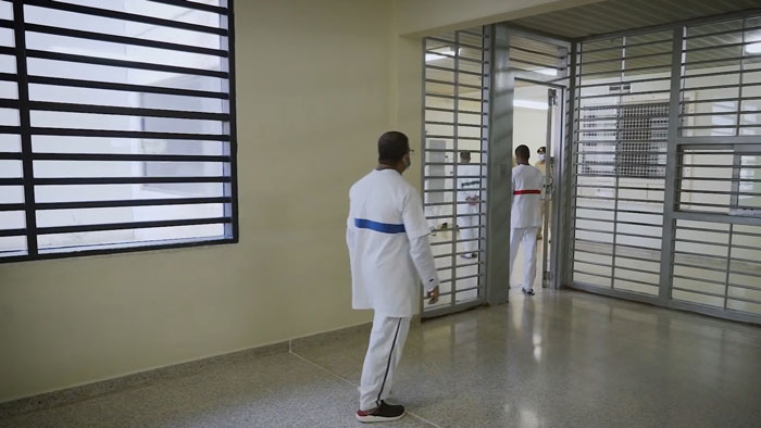 Two men in white uniforms standing inside a secured area of an infamous Dubai prison for British law student substance possession case.