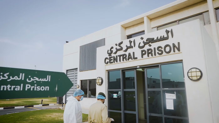 Exterior view of Dubai Central Prison entrance with two men walking nearby, related to glamorous law student case.