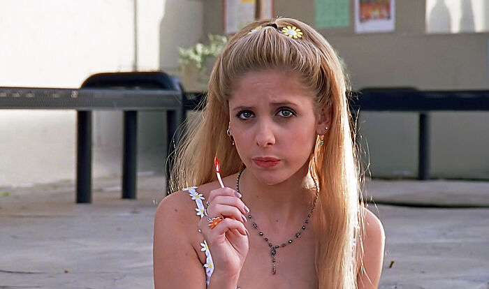 Young woman with long blonde hair holding a tiny object, representing well-written female characters in movies.